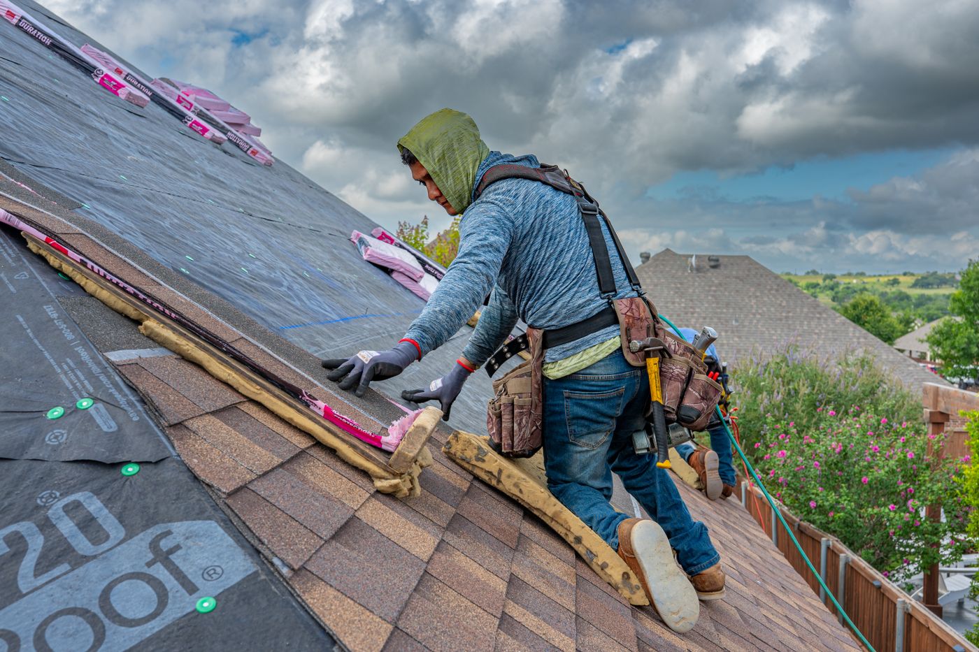 Harness-equipped roofer working on a steep asphalt shingle roof